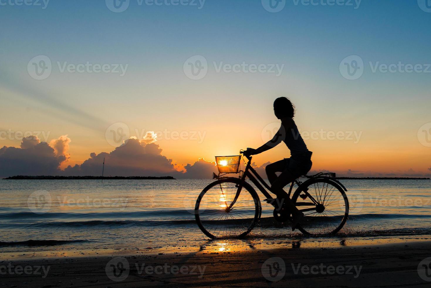 meisje fietsen in de zee tijdens zonsopgang foto