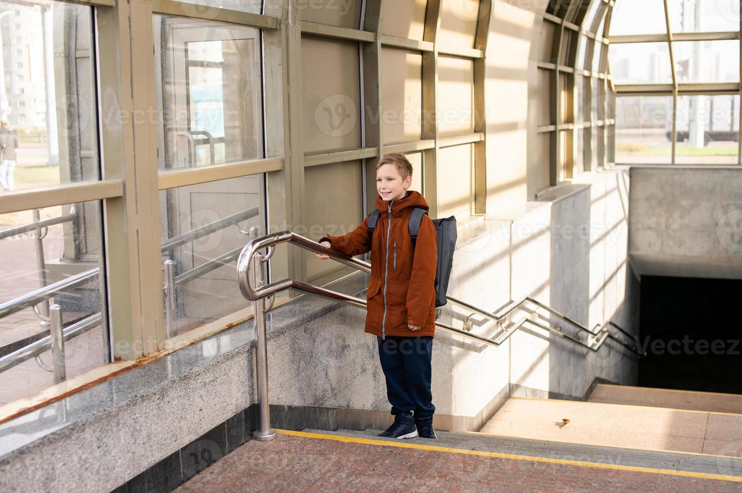 de jongen komt uit van de metro met een rugzak foto