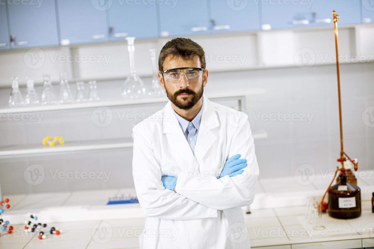jonge wetenschapper in witte laboratoriumjas staande in het biomedische laboratorium foto