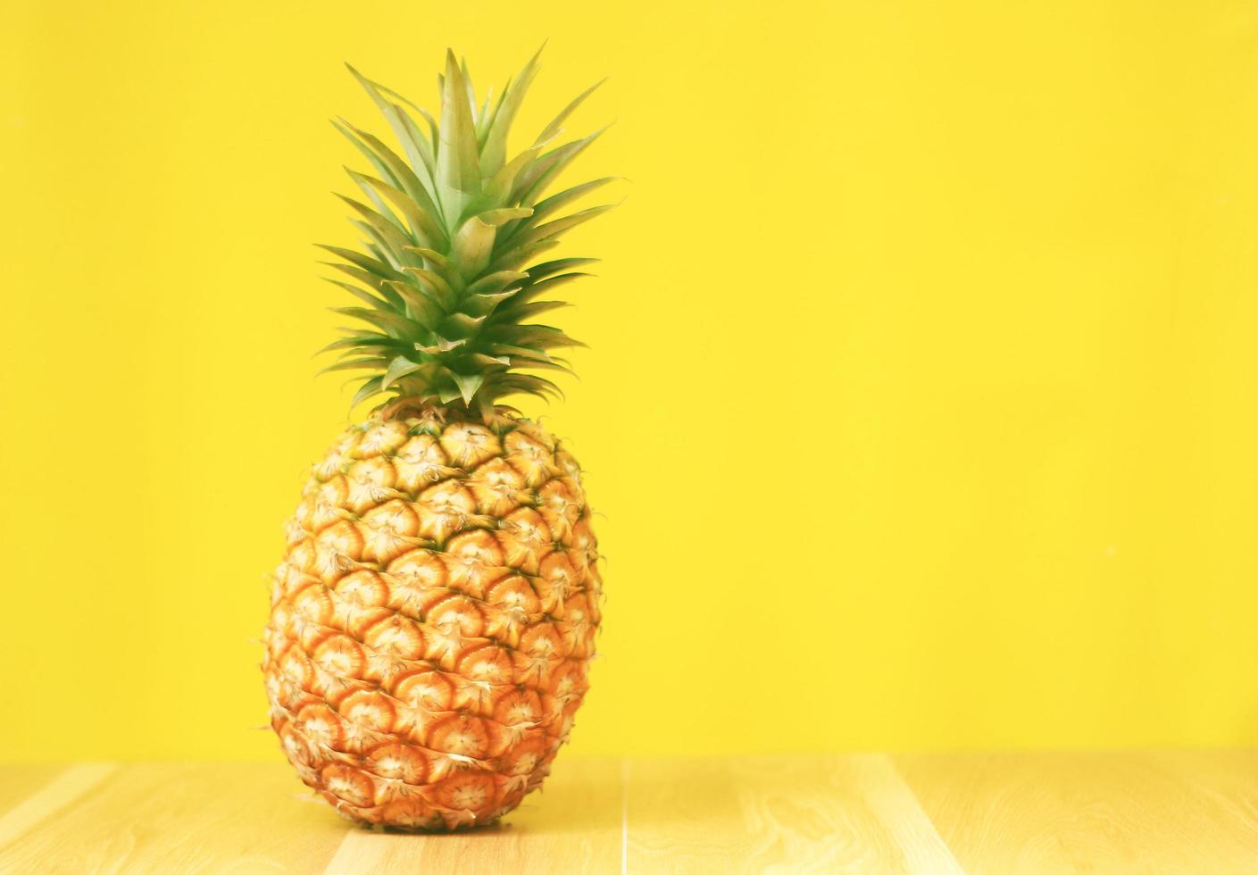 rijpe ananas op een gele houten achtergrond foto