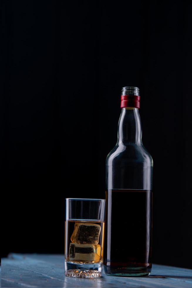 stilleven met glas en fles alcohol op houten tafel foto