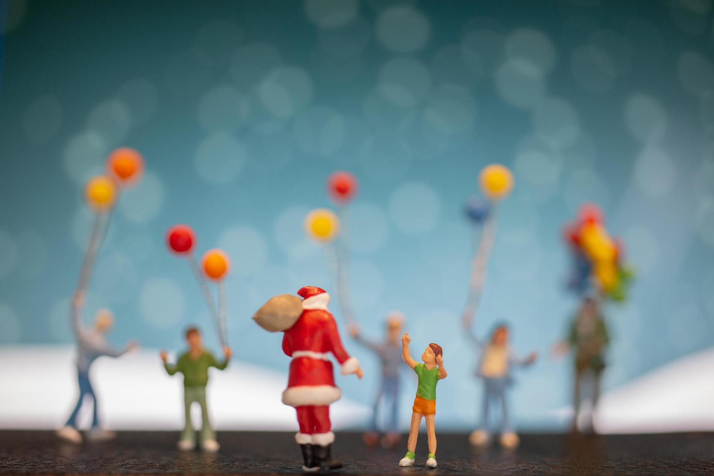 miniatuur kerstman en kinderen met ballonnen, prettige kerstdagen en gelukkig nieuwjaar concept foto