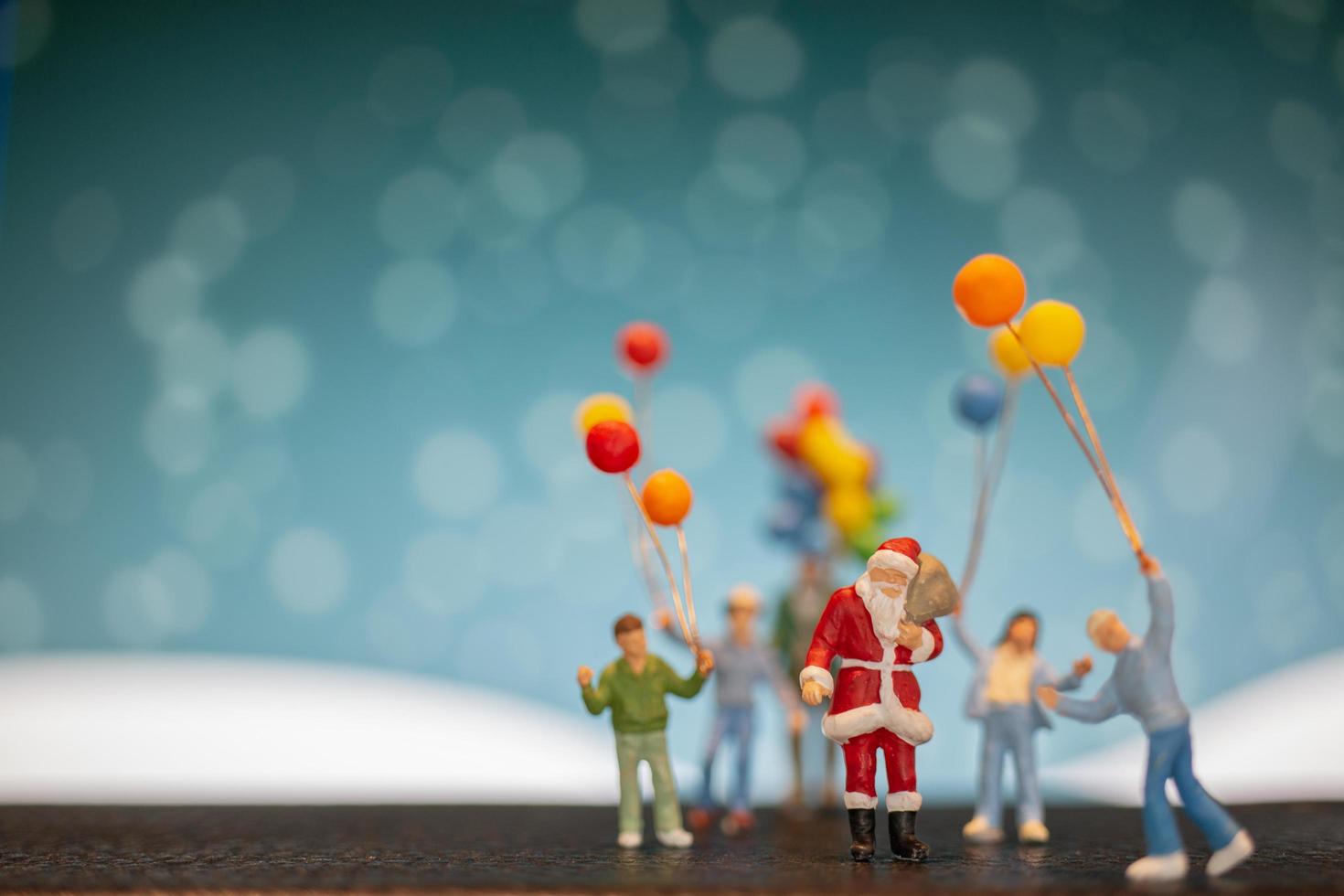 miniatuur kerstman en kinderen met ballonnen, prettige kerstdagen en gelukkig nieuwjaar concept foto