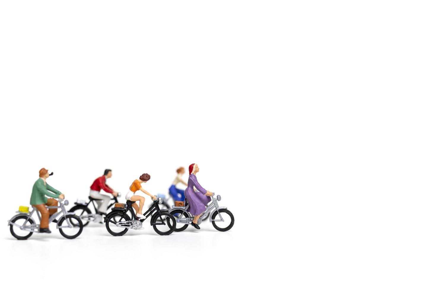 miniatuurvrienden die fietsen berijden die op een witte achtergrond, reisconcept worden geïsoleerd foto