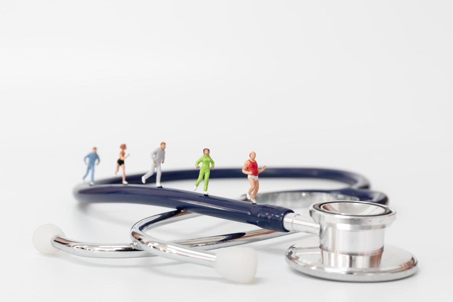 miniatuurmensen die op een stethoscoop, sport en gezond concept lopen foto
