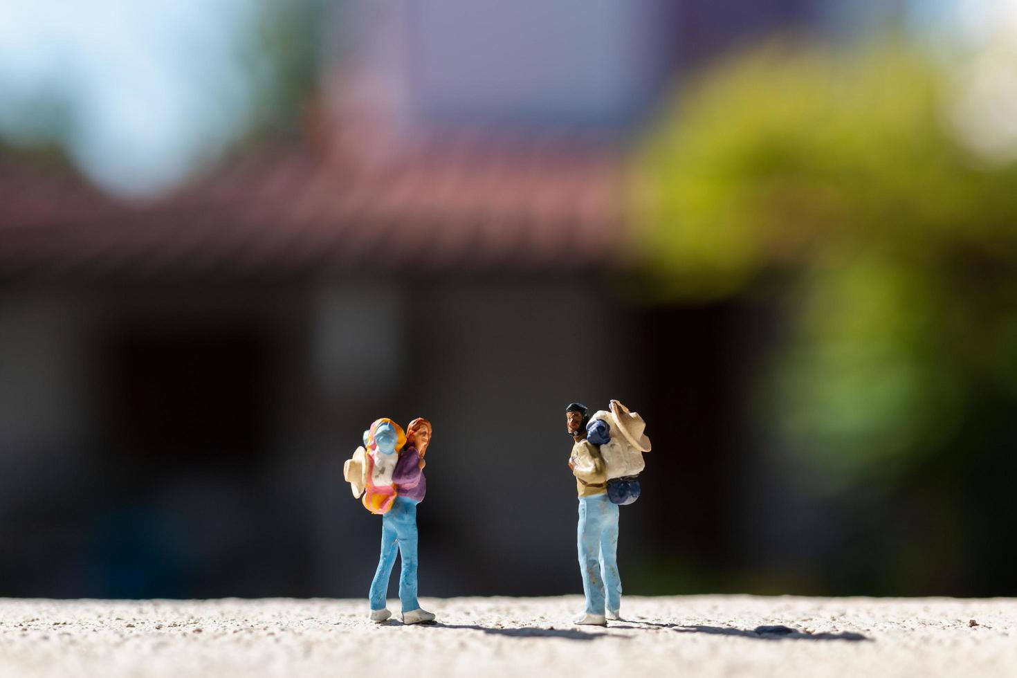 miniatuurreizigers met rugzakken die zich op een weg, reisconcept bevinden foto