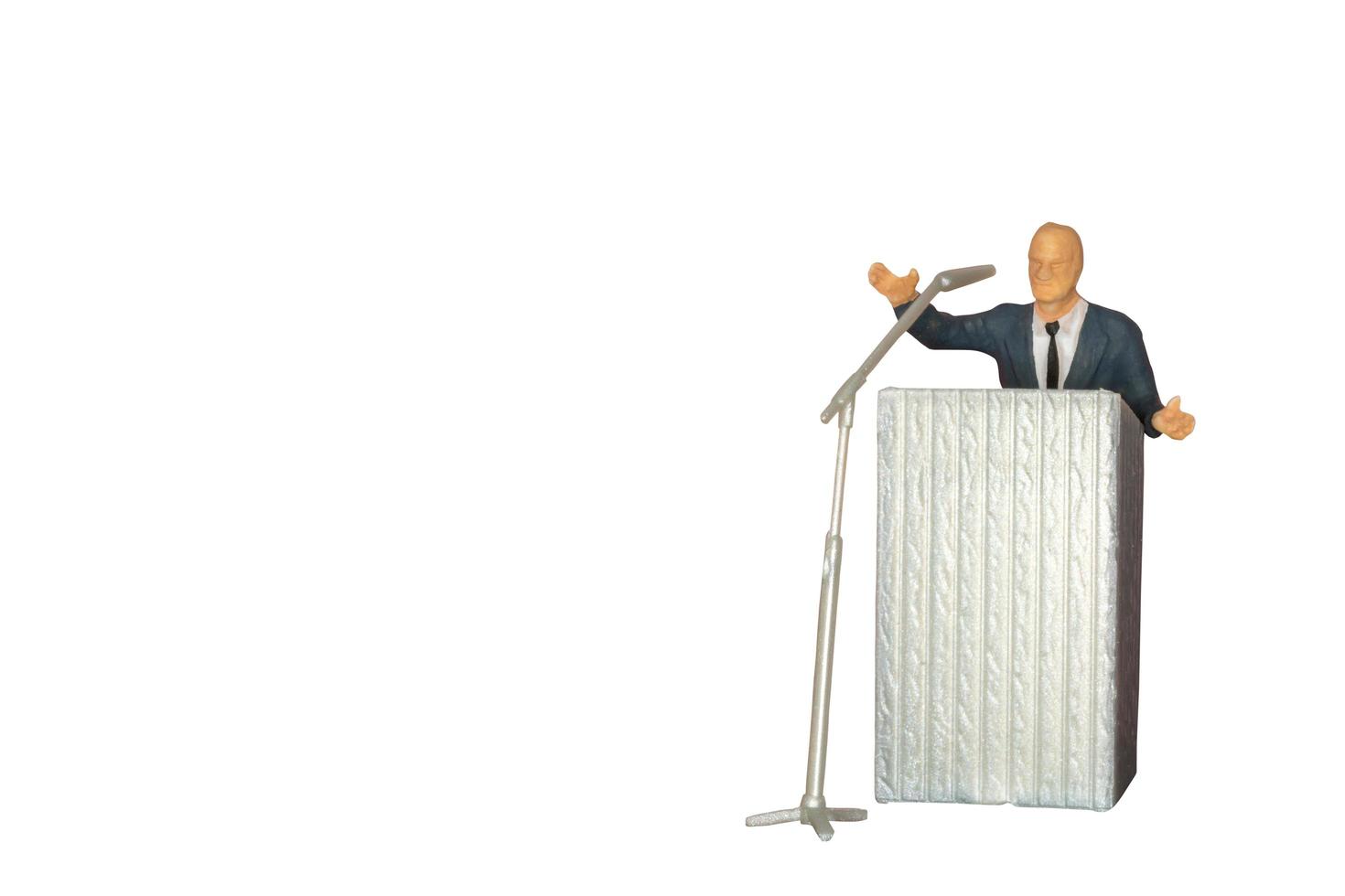 miniatuurpoliticus die met een microfoon spreekt die op een witte achtergrond wordt geïsoleerd foto