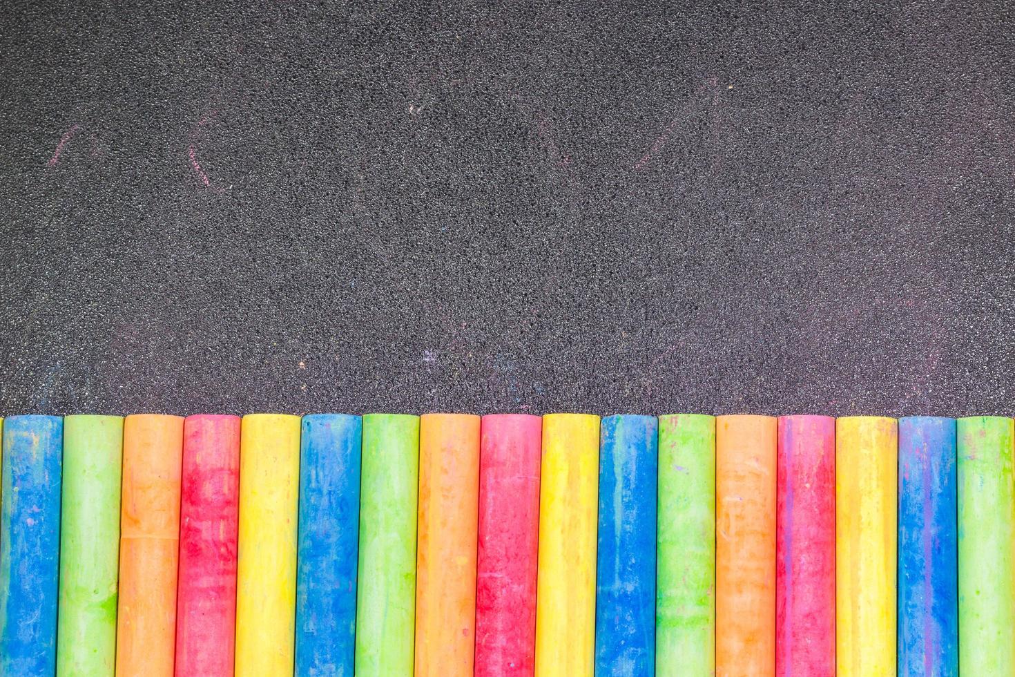 rij van regenboogkleurig krijt op een schoolbord foto