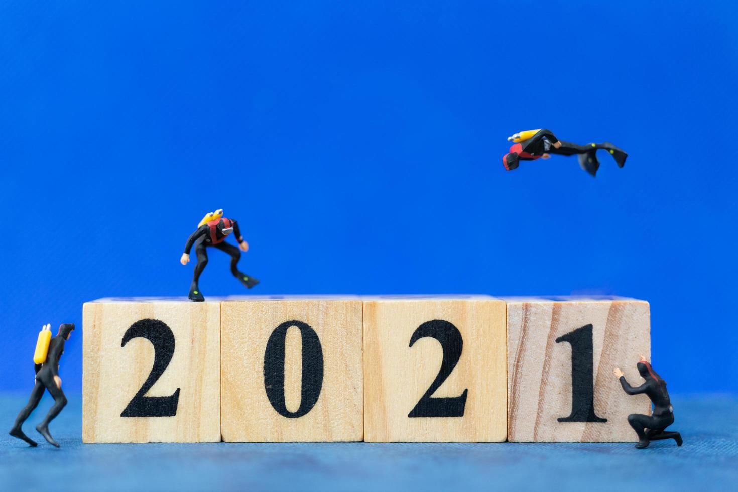 miniatuurduikers die rond houten blokken duiken met het nummer 2021, gelukkig nieuwjaarsconcept foto