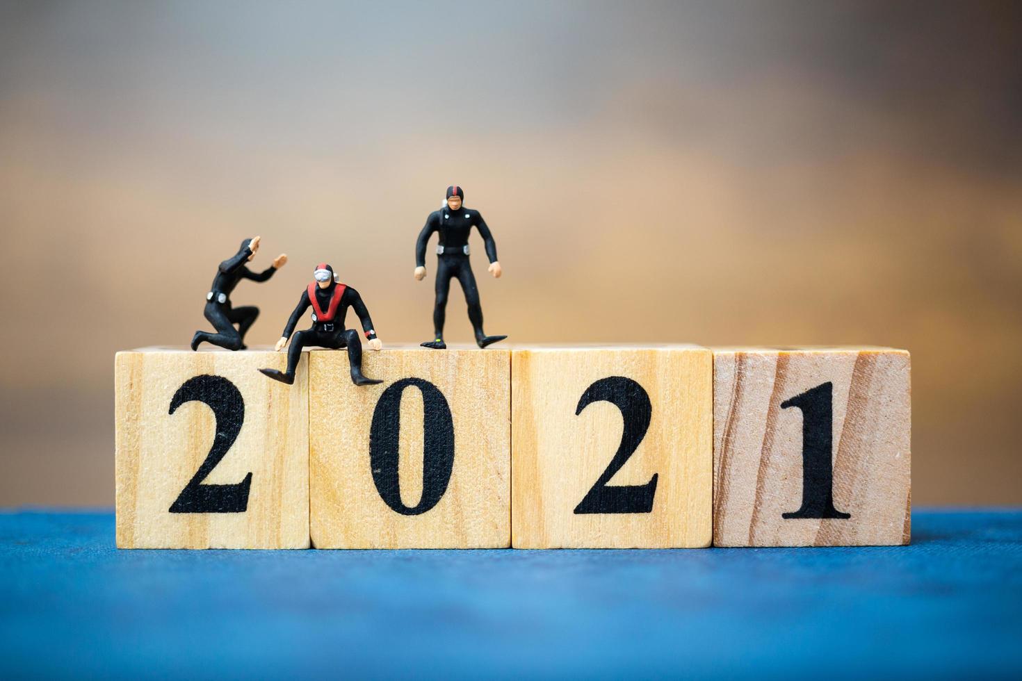 miniatuurduikers die rond houten blokken duiken met het nummer 2021, gelukkig nieuwjaarsconcept foto