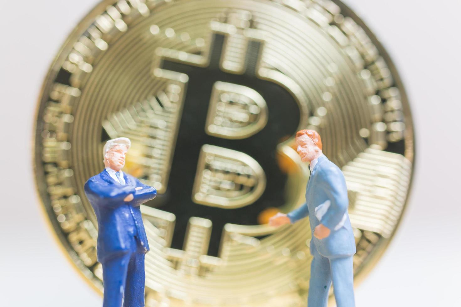 miniatuurzakenlieden die zich voor een bitcoin cryptocurrency-muntstuk bevinden, bedrijfsconcept foto