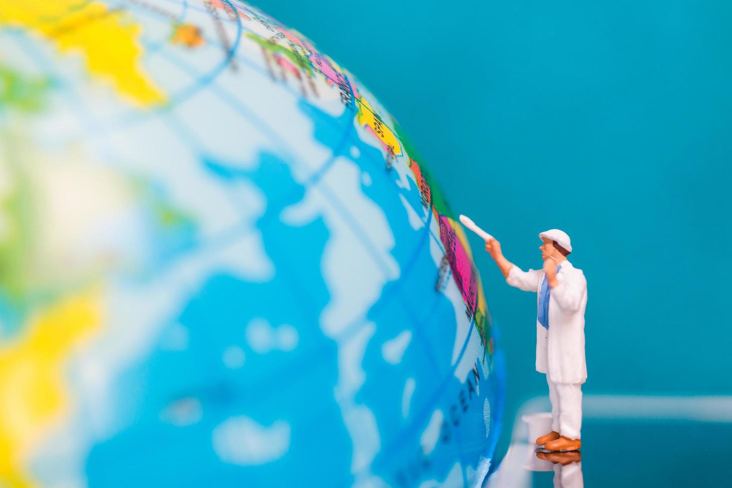 miniatuurschilder die op een bol, het concept van de aardedag schilderen foto