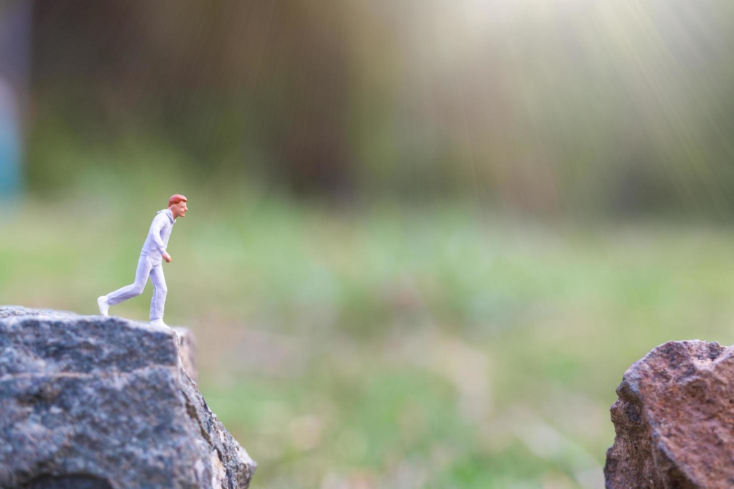 miniatuurmensen die op een rotsklif met aardachtergrond, gezondheids- en levensstijlconcept lopen foto