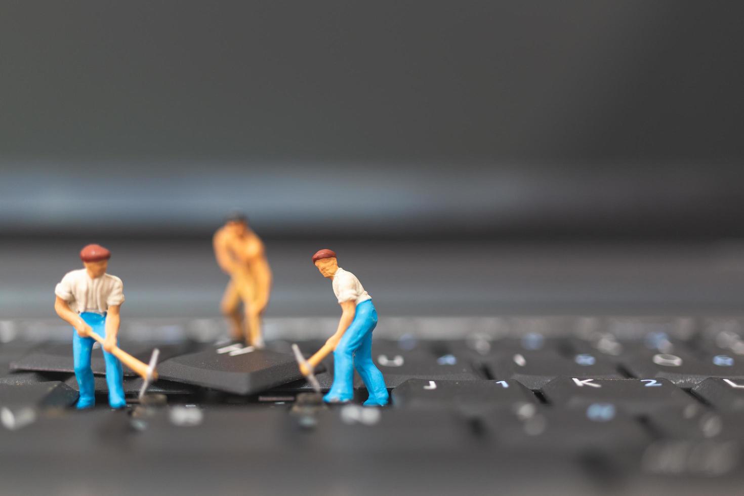 miniatuur team van ingenieurs die een laptop van de toetsenbordcomputer, computerreparatieconcept herstellen foto