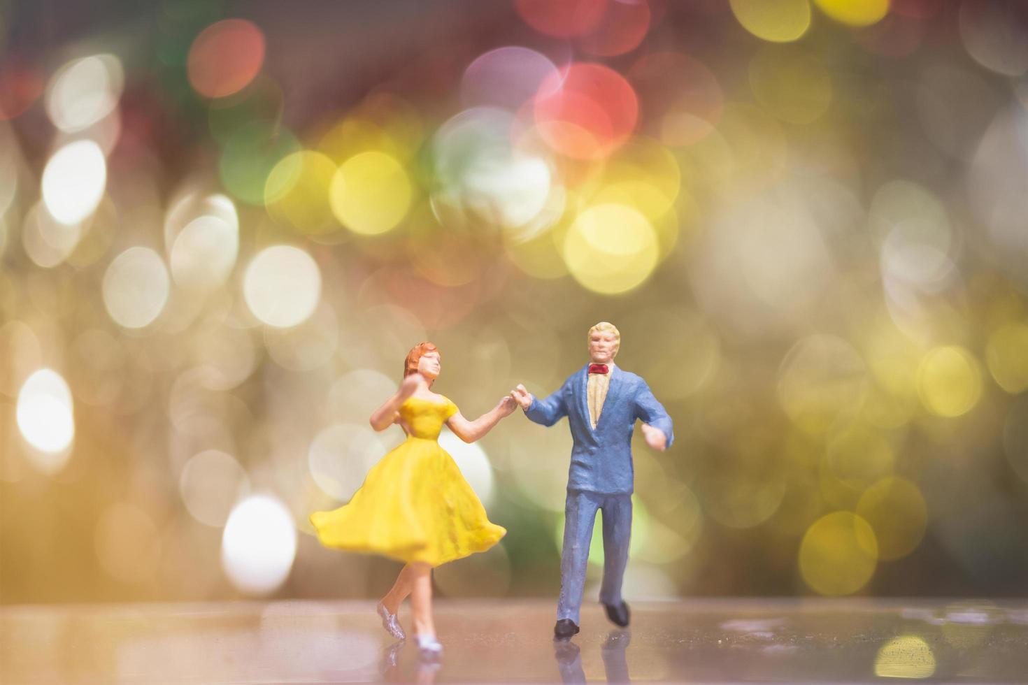 miniatuurpaar dat romantisch met een bokehachtergrond, nachtleven en mensenconcept danst foto
