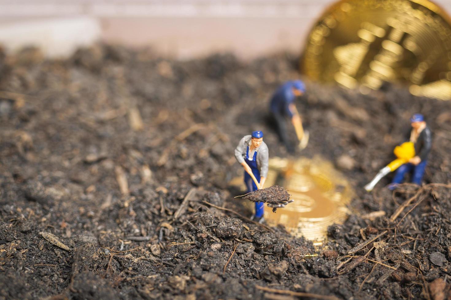 miniatuurarbeiders die de grond graven om glanzende bitcoin cryptocurrency, succesvol werkconcept te ontdekken foto