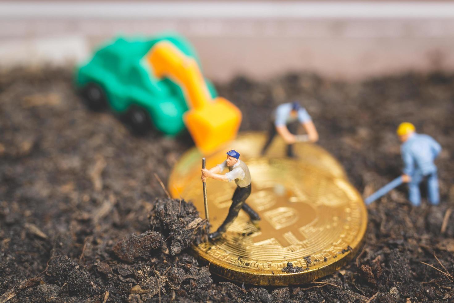 miniatuurarbeiders die de grond graven om glanzende bitcoin cryptocurrency, succesvol werkconcept te ontdekken foto