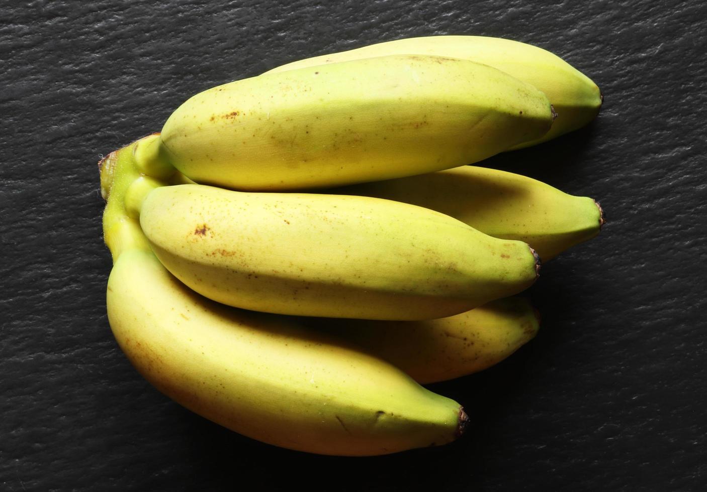 kleine gele bananen op zwarte achtergrond foto