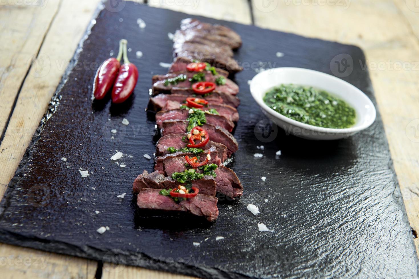 zwarte stenen plaat met roksteak, peper en chimichurri-saus foto