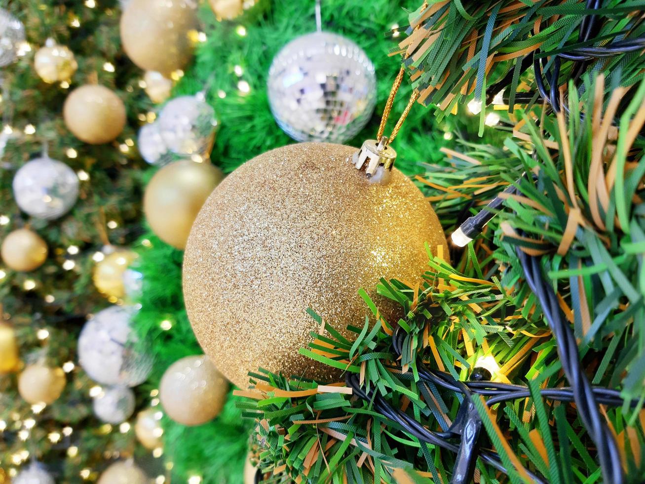 kerstbal opknoping op dennentakken met een feestelijke achtergrond foto
