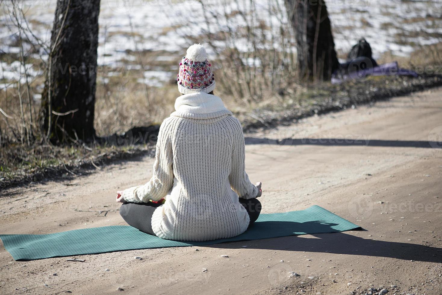 een jonge atletische vrouw voert buiten yoga- en meditatieoefeningen uit foto