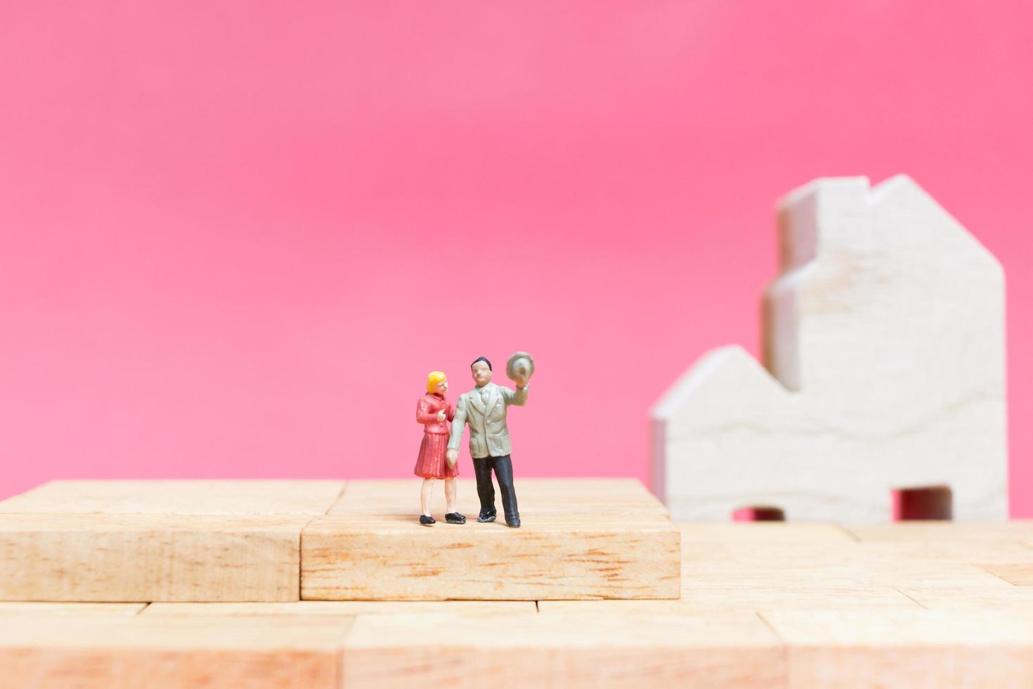 miniatuurpaar met huizen op een roze achtergrond, valentijnsdagconcept foto