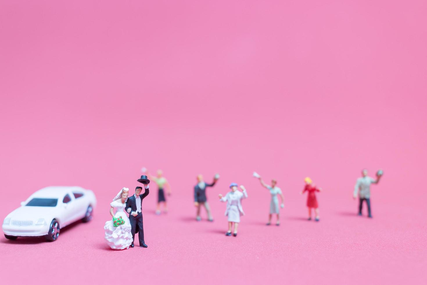miniatuurhuwelijk, een bruid en een bruidegom op een roze achtergrond foto