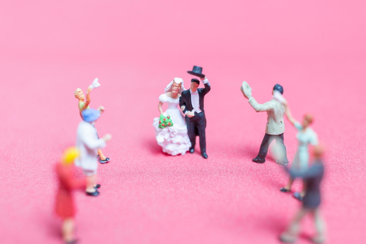 miniatuurhuwelijk, een bruid en een bruidegom op een roze achtergrond foto