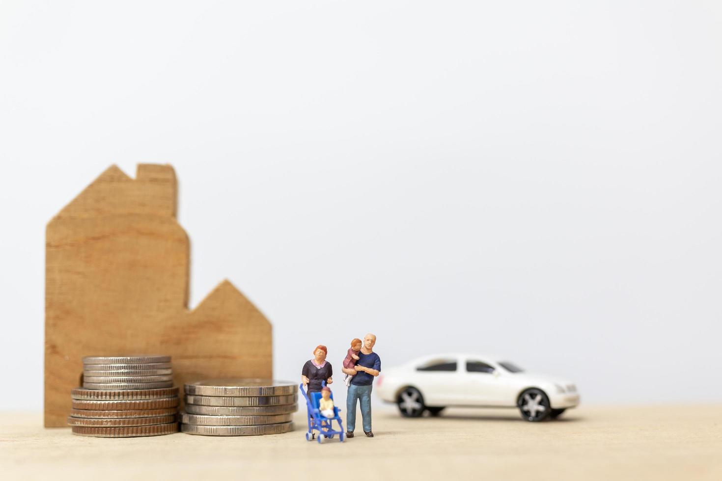 miniatuurouders en kinderen met een huis en een stapel muntstukken, gelukkig familieconcept foto