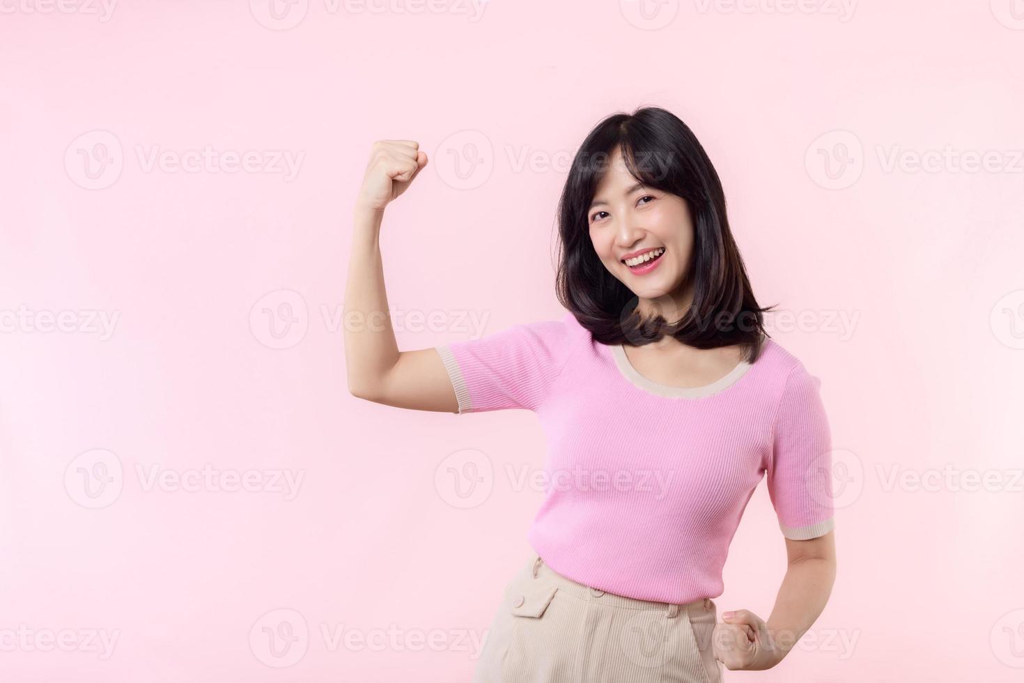 portret jong Aziatisch vrouw trots en zelfverzekerd tonen sterk spier sterkte armen gebogen poseren, voelt over haar succes prestatie. Dames machtiging, gelijkwaardigheid, gezond sterkte en moed concept foto