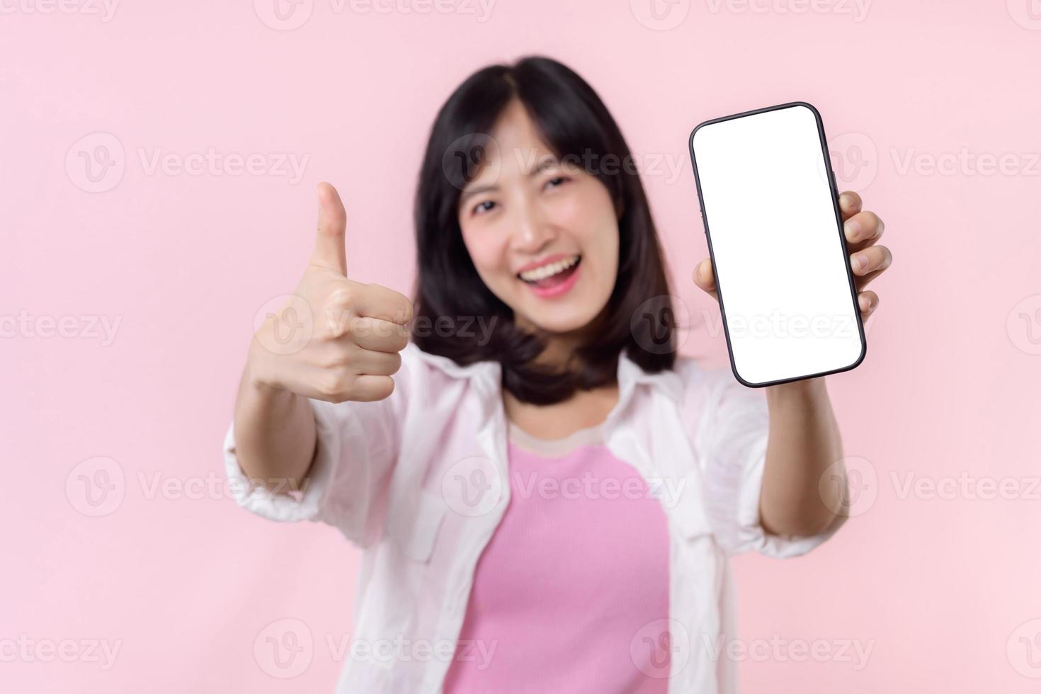 gelukkig glimlachen jong Aziatisch vrouw aanbevelen tonen nieuw toepassing of mobiel advertentie, mockup smartphone sjabloon banier geïsoleerd Aan roze achtergrond. collage blanco scherm digitaal mobiel apparaat. foto