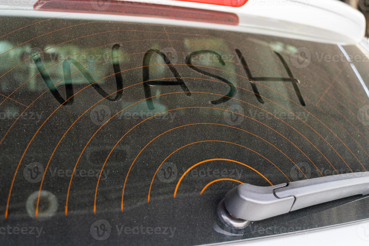 vuil achterzijde venster van de auto en opschrift wassen. wassen tekst Aan vuil auto. foto