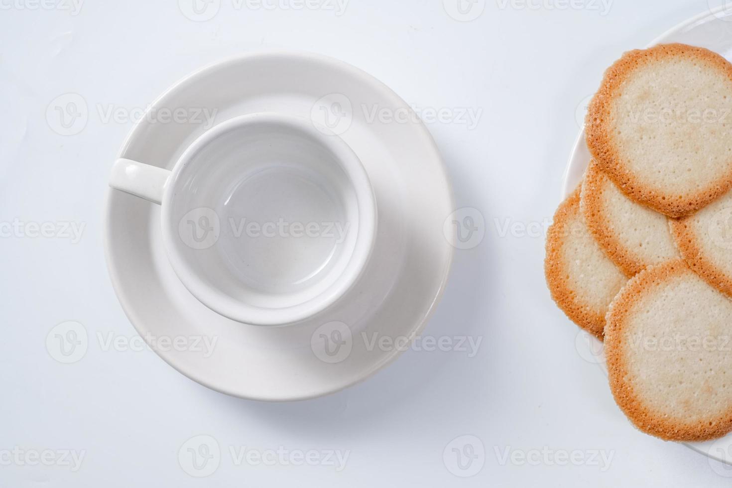 lege koffiemok met koekjes op witte achtergrond foto