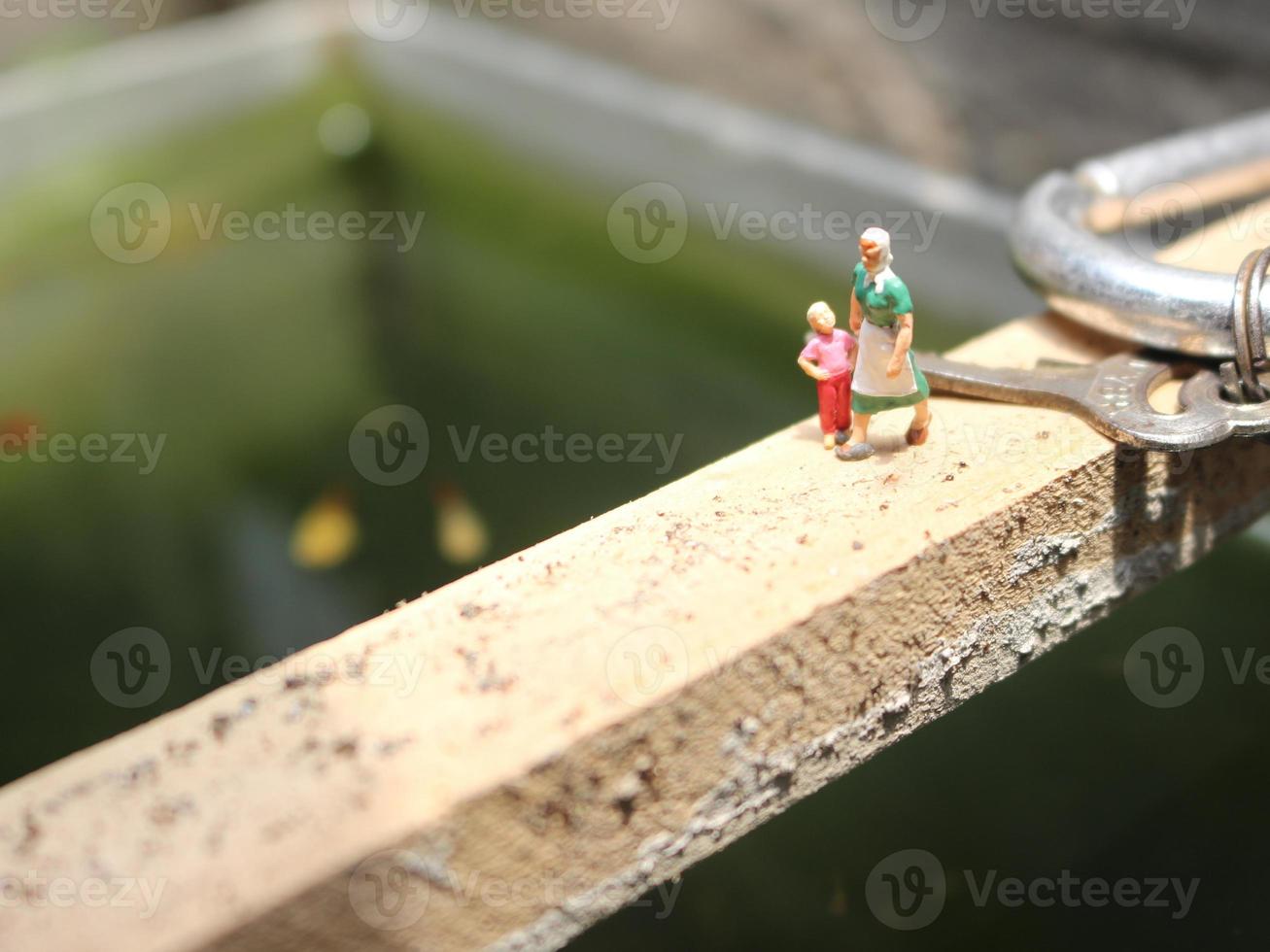 miniatuur figuren van moeder en kind wandelen Aan een vis vijver. foto