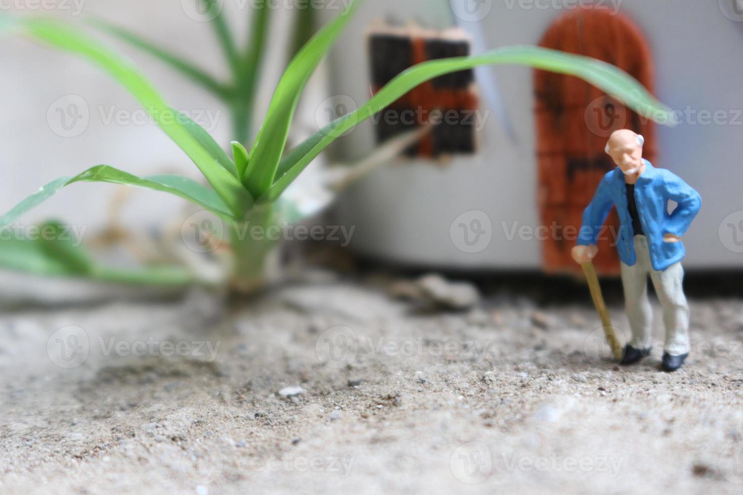 miniatuur figuur van een opa wie is aan het wachten in voorkant van de huis. foto