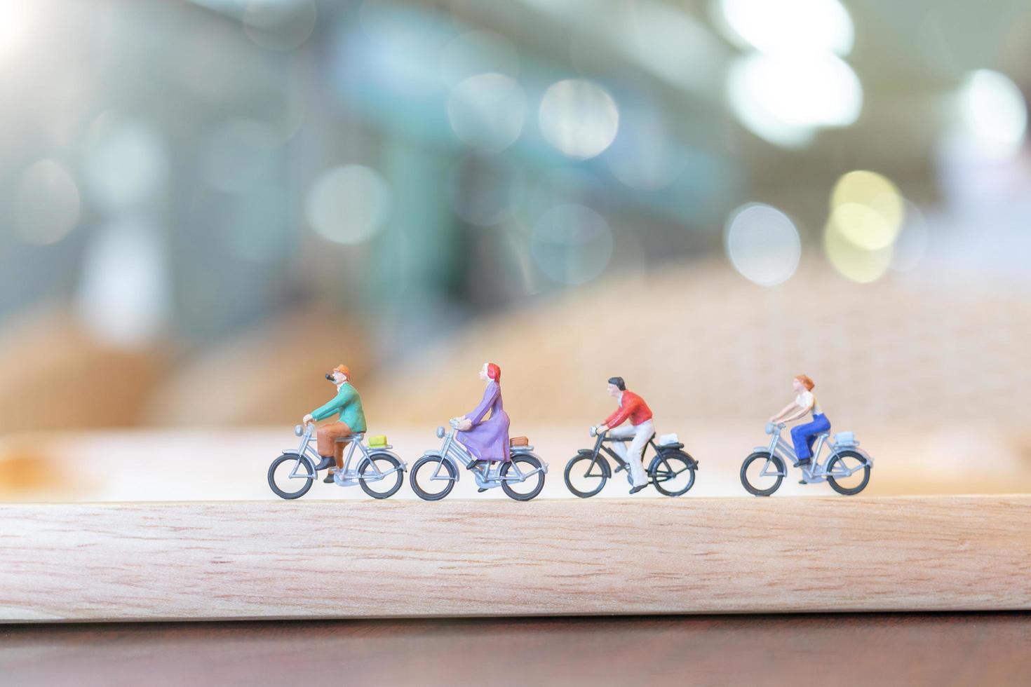 miniatuurmensen fietsen op een houten brug, zorgconcept foto
