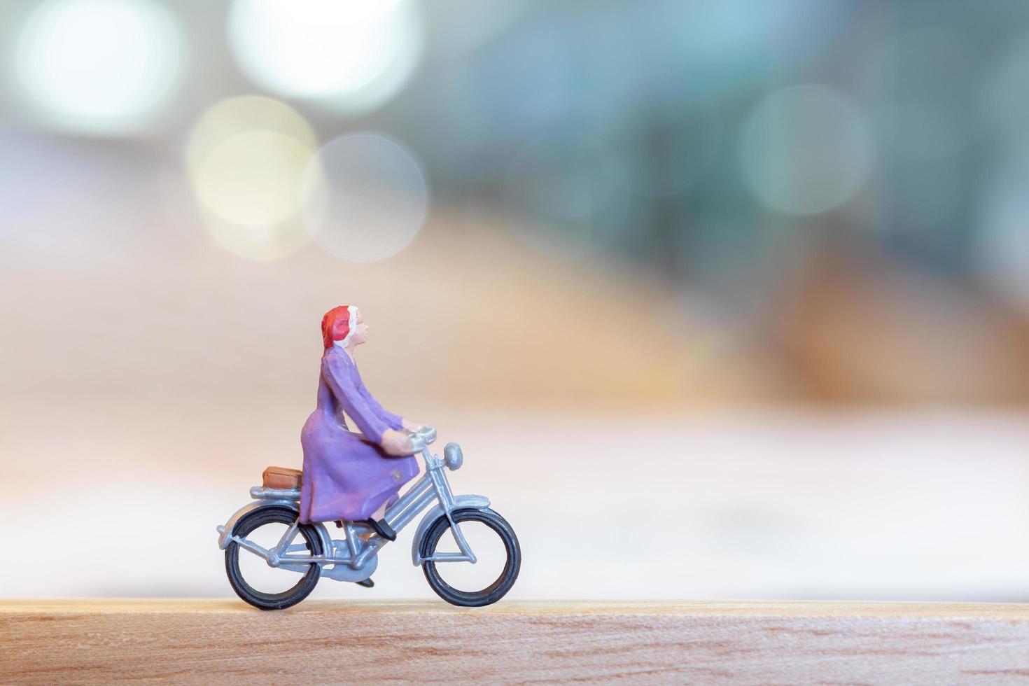 miniatuurpersoon fietsen op een houten brug, zorgconcept foto