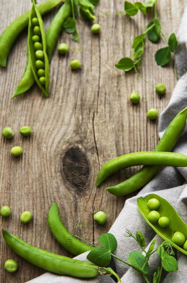 peulen van groene erwten met erwtenbladeren op een oude houten achtergrond foto