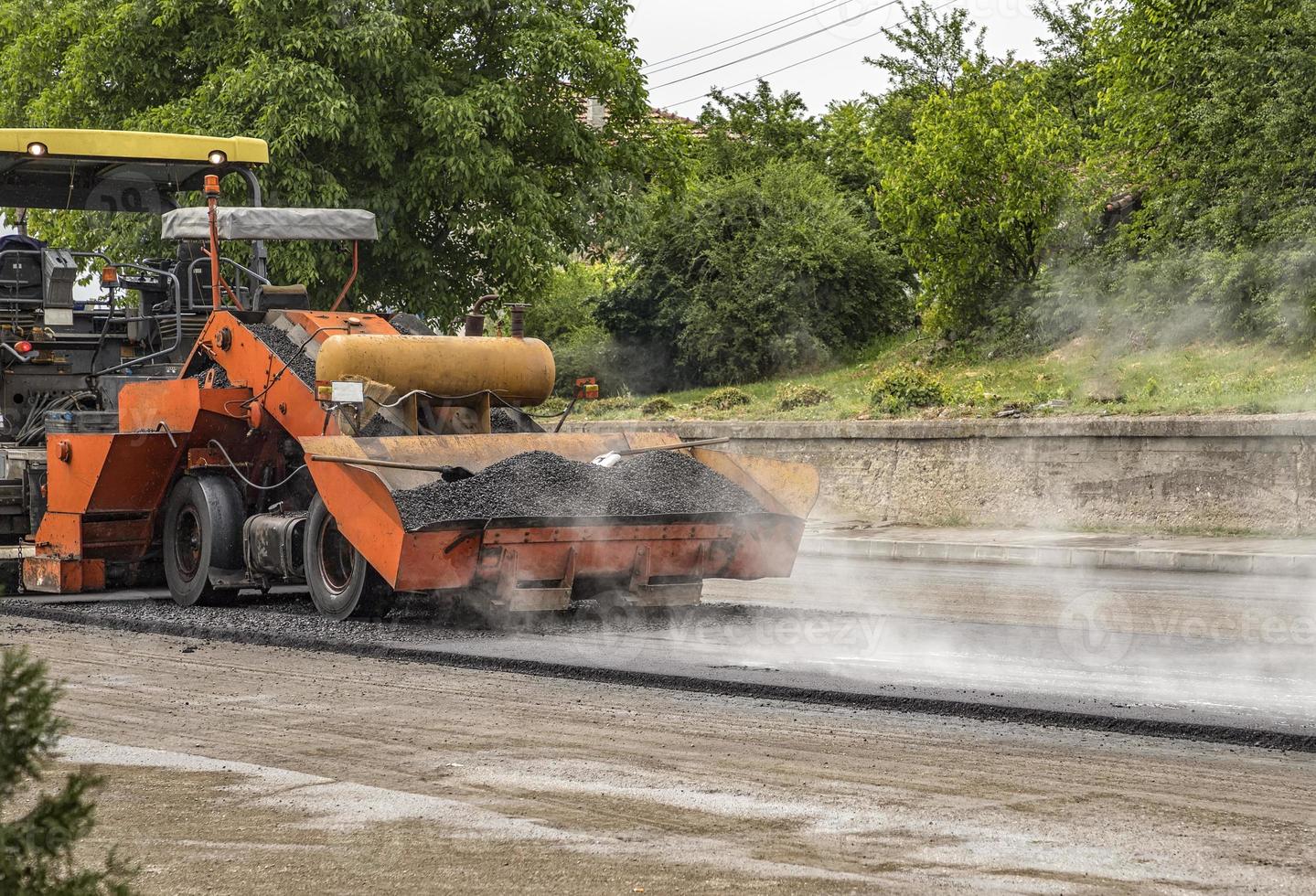 asfalt bestratingsafwerkmachine machine maakt een nieuw weg en repareren werken. een bestratingsafwerkmachine afmaker, asfalt afwerker of bestrating machine plaatsen een laag van asfalt. herbestraten. foto