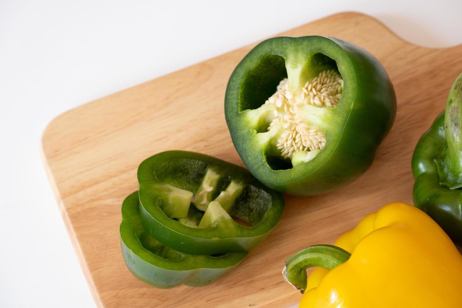 top visie van snijdend zoet klok peper Aan de houten bord geïsoleerd Aan wit achtergrond. foto