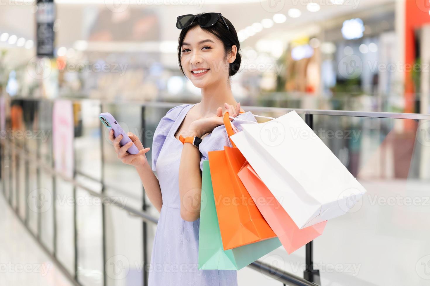 gelukkig Aziatisch vrouw boodschappen doen Bij winkelcentrum foto