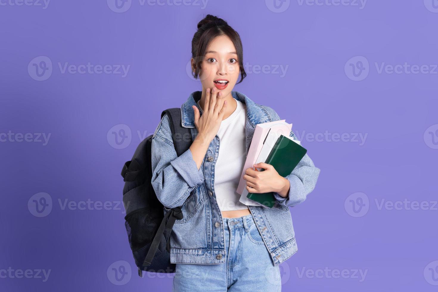 portret van een mooi Aziatisch schoolmeisje vervelend een rugzak Aan een Purper achtergrond foto