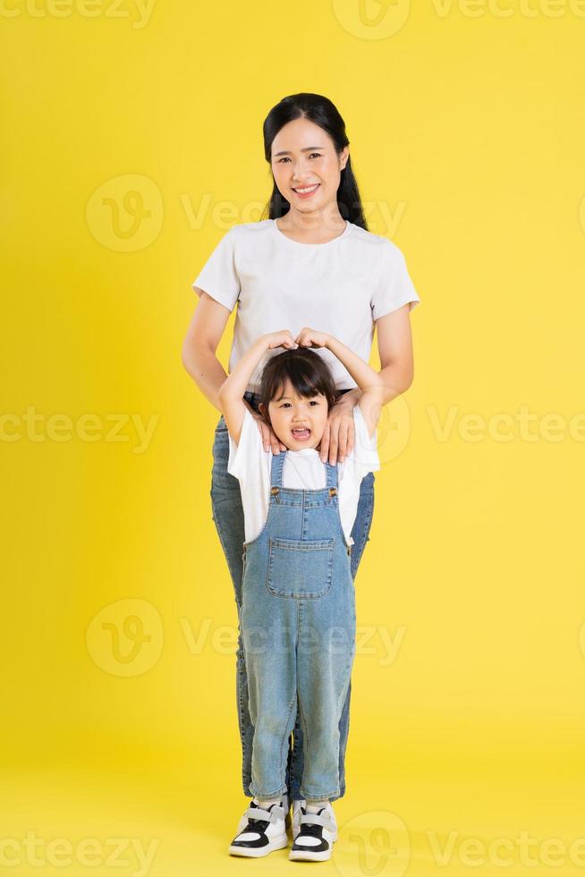 beeld van Aziatisch moeder en dochter poseren Aan een geel achtergrond foto