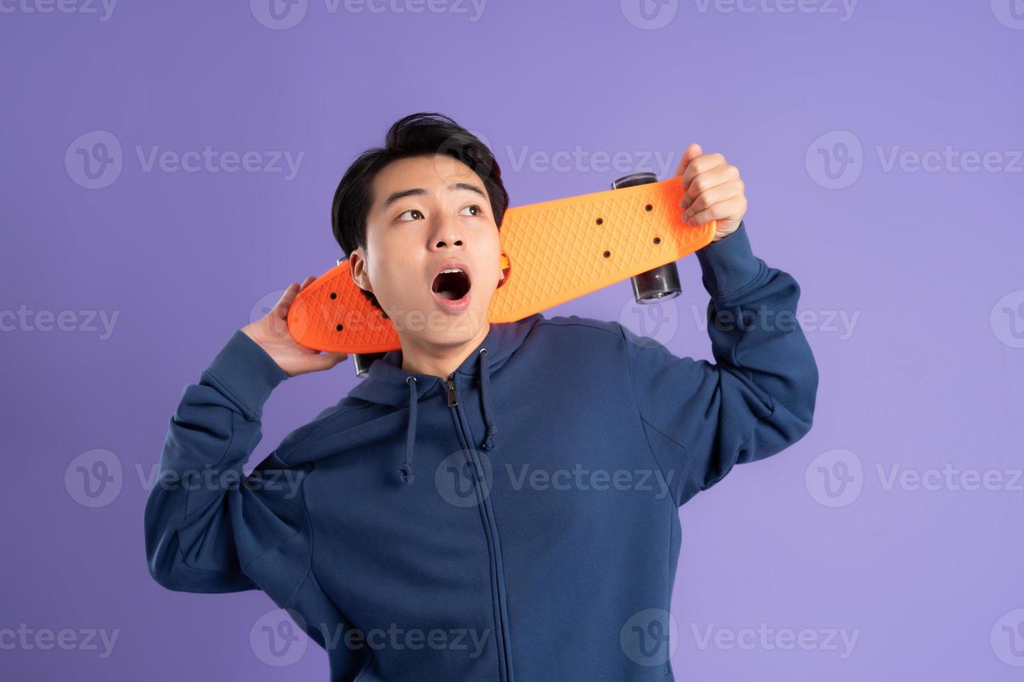 beeld van jong Aziatisch Mens spelen skateboard Aan Purper achtergrond foto