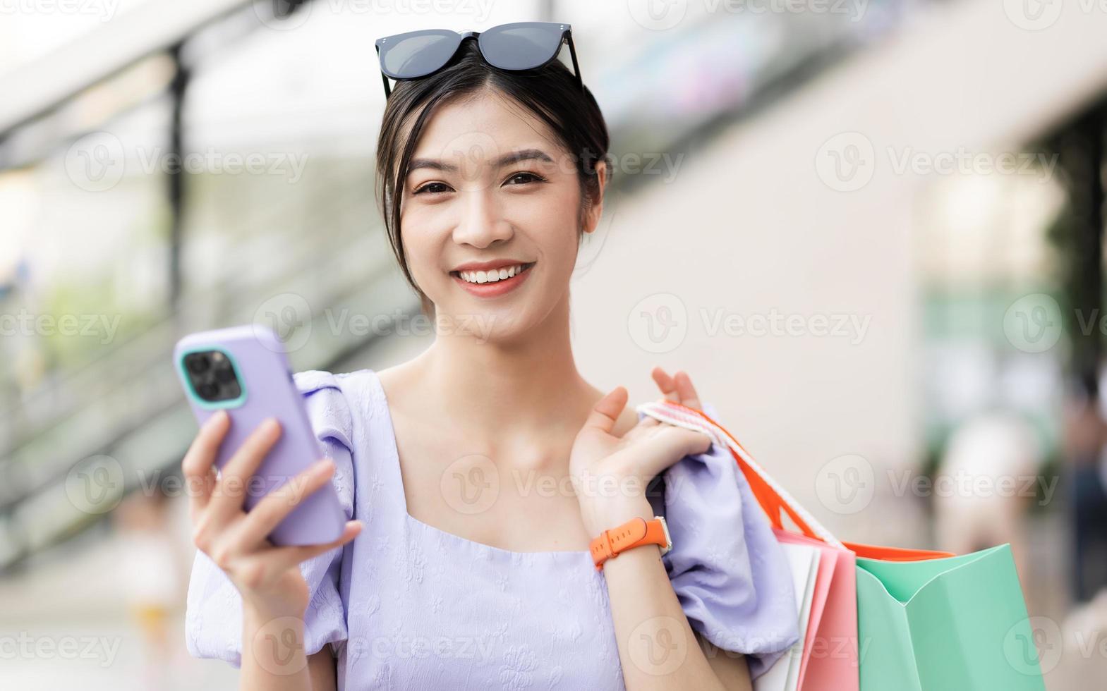 gelukkig Aziatisch vrouw boodschappen doen Bij winkelcentrum foto