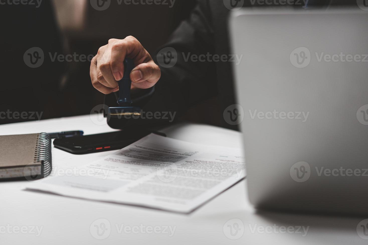 zakenman hand- stempelen goedgekeurd Aan certificaat document contract in kantoor. advocaat stempelen toestaan Aan papierwerk Bij houten bureau. foto