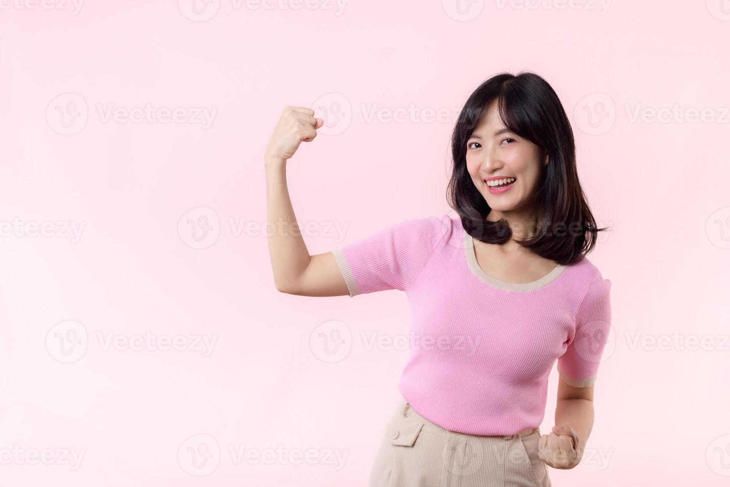 portret jong Aziatisch vrouw trots en zelfverzekerd tonen sterk spier sterkte armen gebogen poseren, voelt over haar succes prestatie. Dames machtiging, gelijkwaardigheid, gezond sterkte en moed concept foto