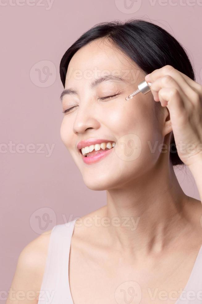 mooi jong Aziatisch vrouw toepassen serum gelaats olie Aan natuurlijk mack omhoog gezicht huid. portret Gezondheid welzijn schoon huidsverzorging vrouw aantrekkelijk persoon met behandeling druppelaar. schoonheid, schoonheidsspecialiste concept foto