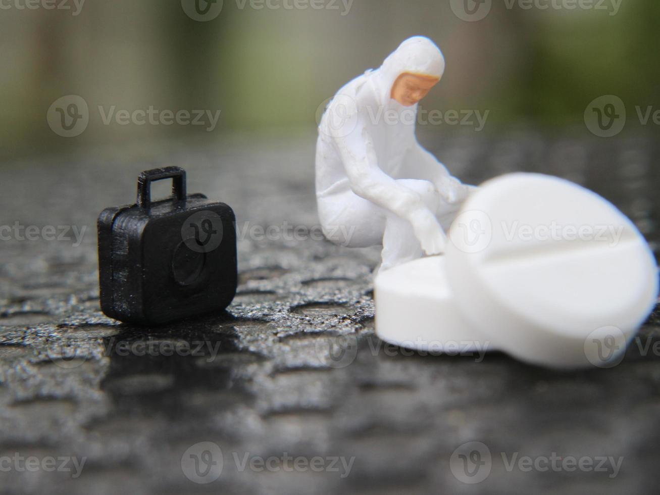 een dichtbij omhoog van een miniatuur figuur van een onderzoeker onderzoeken een medicijn. Gezondheid foto concept.