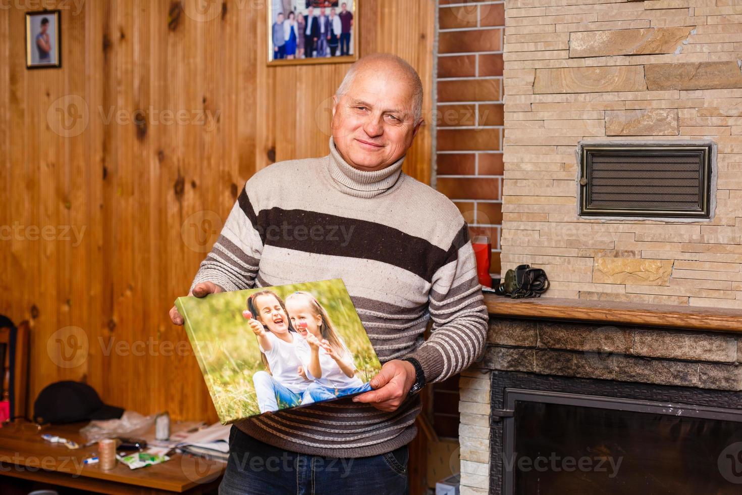 ouderen Mens Holding een foto canvas in een houten huis